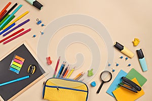 Flat lay photo of workspace desk with school accessories or office supplies on pink background.