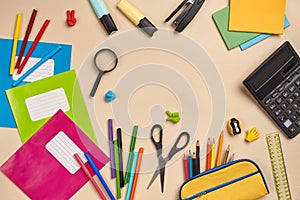 Flat lay photo of workspace desk with school accessories or office supplies on pink background.
