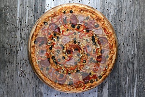 Flat lay photograph of tasty italian pizza on rustic wood. Pepperoni, cheese and peppers. Delicious food.