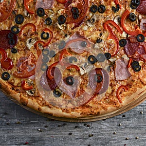 Flat lay photograph of tasty italian pizza on rustic wood. Pepperoni, cheese and peppers. Delicious food.