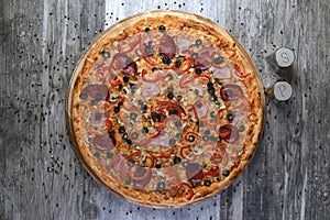 Flat lay photograph of tasty italian pizza on rustic wood. Pepperoni, cheese and peppers. Delicious food.