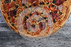 Flat lay photograph of tasty italian pizza on rustic wood. Pepperoni, cheese and peppers. Delicious food.