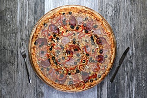 Flat lay photograph of tasty italian pizza on rustic wood. Pepperoni, cheese and peppers. Delicious food.