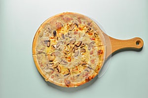 Flat lay photograph of tasty Italian pizza on rustic wooden board. Cheese and mushrooms.