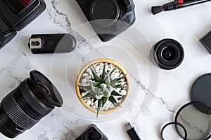 Flat lay of photography equipment on white marble background: dslr camera and lens. Photographer workspace concept. Top view