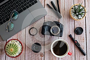 Flat lay of photography equipment on wooden desktop background: dslr camera, laptop and lens. Blogger workspace concept. Top view