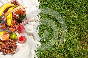 Flat lay Picnic on a green lawn, with a plaid fruit and picnic basket and a bottle of wine and glasses with red wine, with space.