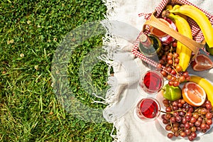 Flat lay Picnic on a green lawn, with a plaid fruit and picnic basket and a bottle of wine and glasses with red wine, with space.