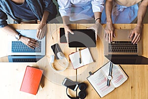 Flat lay picture of three women working with laptops and books sitting at the table together