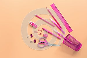 Flat lay pink stationery on a pastel background. Top view, copy space. Glass, scissors, pencil, pen, ruler, eraser and paper clip