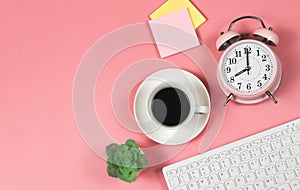 Flat lay of pink vintage alarm clock 8 0`clock, a cup of black coffee, computer keyboard, sticky note paper and succulent plant
