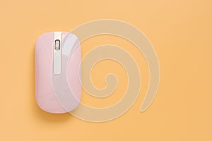 A flat lay pink wireless computer mouse on a yellow pastel background. Minimal creative layout. Female workspace. Top view, copy