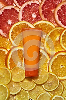 Flat lay of plastic orange tube with natural vitamin C skin care product isolated over fresh juicy orange citrus fruit