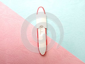 Flat Lay Plastic Pregnancy test pack positive result at texturized Pink and Blue Paper Background