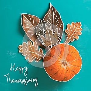flat lay pumpkin and autumn dry leaves with handwriting text happy thanksgiving on a blue background