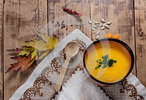 Flat lay pumpkin soup bowl on rustic wooden background