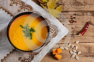 Flat lay pumpkin soup bowl on rustic wooden background
