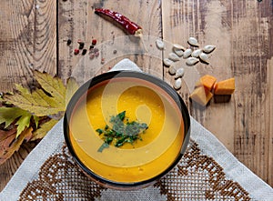 Flat lay pumpkin soup bowl on rustic wooden background