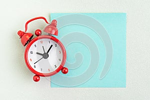 Flat lay of red alarm clock with blank sticky note for message on white background with copy space using as time, deadline, stop