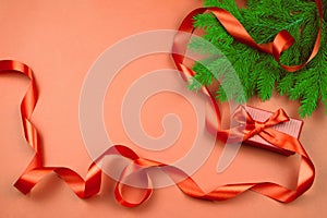 Flat lay with red gift box, red ribbon and Christmas tree branch on red background.