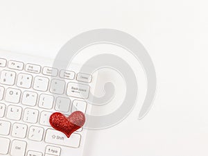 flat lay of red glitter hearts on white computer keyboard on white background. online dating or valentines day concept