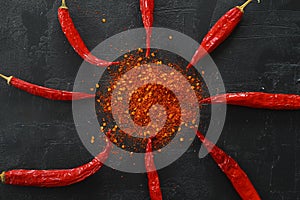 Flat lay red hot Chili peppers, red pepper flakes and chilli powder on black background.