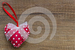 Flat lay red pillow heart with white dots and a bow and on wooden background with copy space for your text