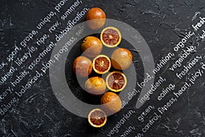 flat lay of red sliced exotic oranges, dark food on black surfaces
