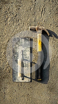 Flat lay of rusty metal hammer and finishing trowel on grunge cement background