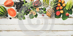 Flat-lay of seasonal fruit, vegetables and greens over wooden background