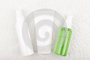 Set of cosmetic bottles for face washing, exfoliating and moisturizing on white flossy towel photo