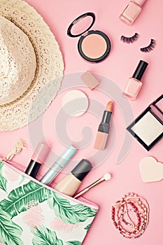 Flat lay with set of professional decorative cosmetics, makeup tools and woman spring, summer accessories over pink background