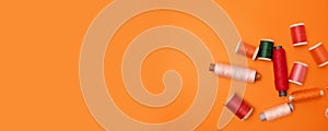 Flat lay of sewing colored threads on an orange background with copyspace