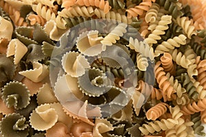 Flat lay of short pasta of various colors and shapes such as fusilli and daisies