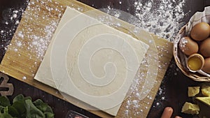 Flat lay shot: chef rolls out the dough with a rolling pin on the kitchen table, table top of the rolling out the puff