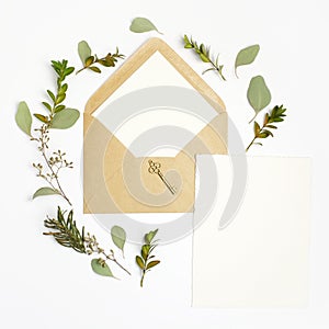 Flat lay shot of letter and eco paper envelope on white background. Wedding invitation cards or love letter with plant