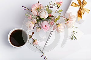 Flat lay shot of letter and white envelope on white background with pink english rose. Invitation cards or love letter