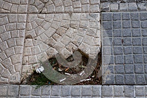 Flat lay of a sidewalk with broken tiles where dirt accumulates