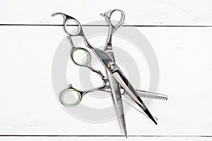 Flat lay with silver hairdressing scissors. Barber scissors on white wooden background