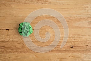 Flat lay of single green crumpled paper on wooden table background copy space. Business brainstorming in office company