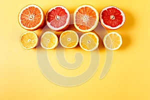 Flat lay slices of different raw fresh citrus fruit over yellow background