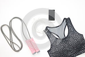 Flat lay of smartphone, sport bra and sport equipments on white