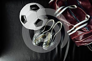 Flat lay soccer football accessories on a dark leather background. Mock-up with copy space for text.