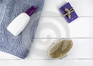 Flat lay spa bath on white wooden background, top view products for hygiene. Brush, soap and tube with towel