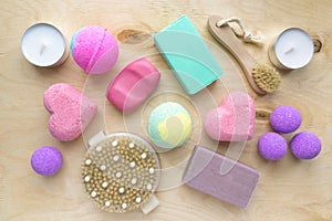 Flat lay of spa products. Soap, bath bombs, massage brushes and candles on wooden background, top view