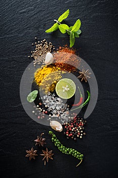 Flat-lay of spices and herbs on black background. Ingredients for cooking. Food background on stone. Top view copy space