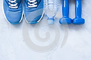 Flat lay sport shoes, bottle of water and dumbbells