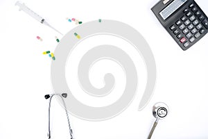 Flat lay of stethoscope with calculator and pills