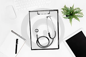 Flat lay with stethoscope, clipboard, empty notebook and digital devices