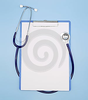 Flat lay of stethoscope and writing pad paper clip board on light blue background with copy space, healthcare and medical concept